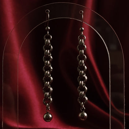 Pair of silver chain earrings on a red satin background